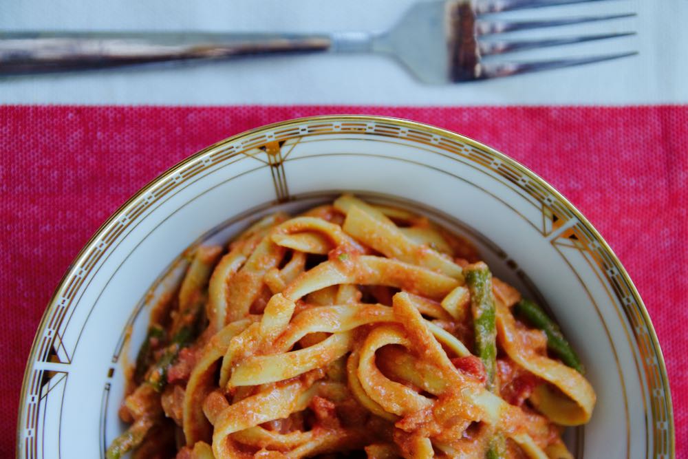 fettuccine with sweet tomato sauce and asparagus on a red and white tablecloth