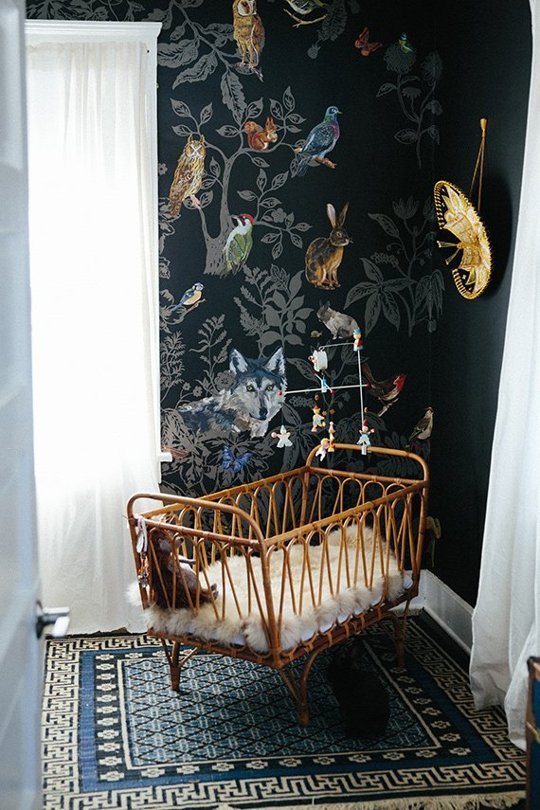 super cool nursery with a black wall and a wicker crib