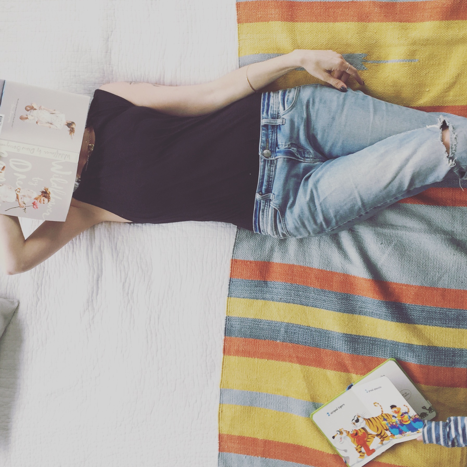 White bed with a striped rug used as a throw blanket