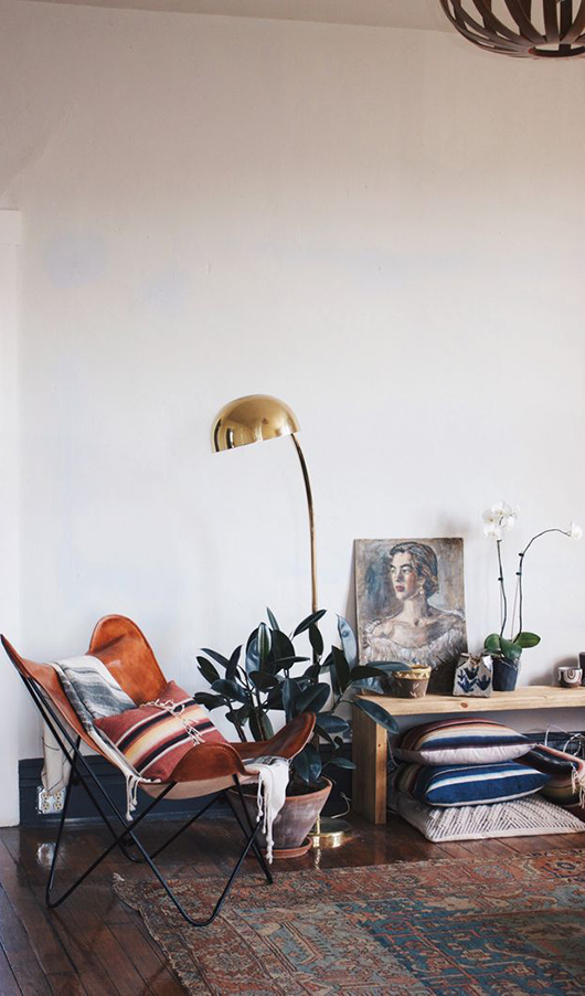 Amazing folding leather chair with a gold midcentury lamp and vintage rug