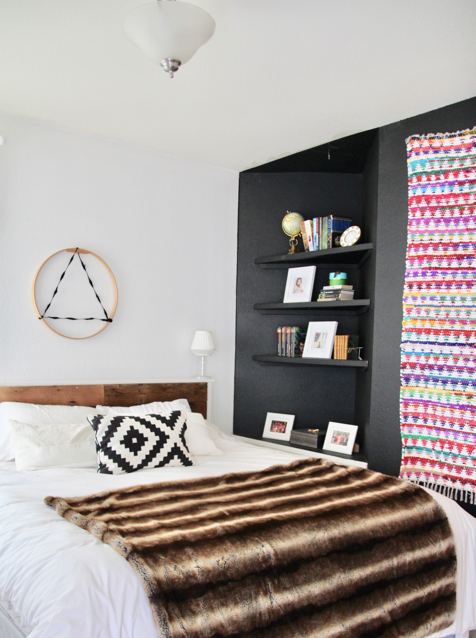 one black wall in an all white bedroom
